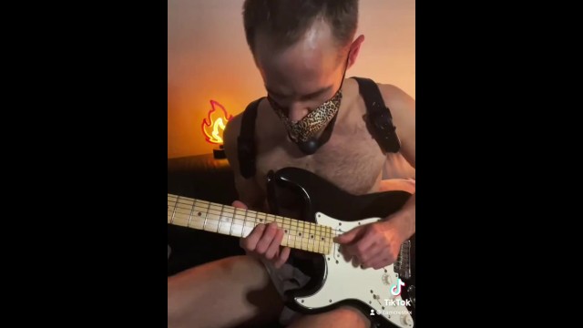Guy with a ball gag plays guitar