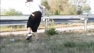 Girl shitting outdoor close to the road