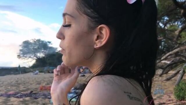 Beautiful brunette girl smoking & playing on beach